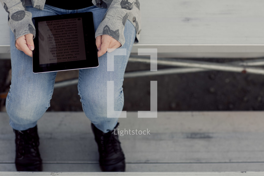 Teenage girl reading bible on an iPad,  1 Timothy 4:12,  bleachers, youth, student technology, study, devotional