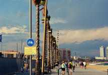 tourists walking on sidewalks near a beach 