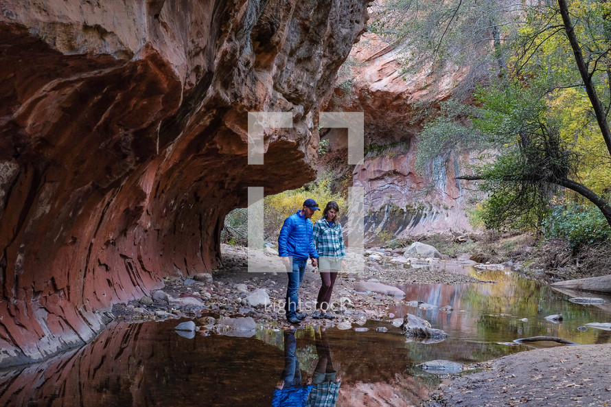 a couple hiking across a stream 