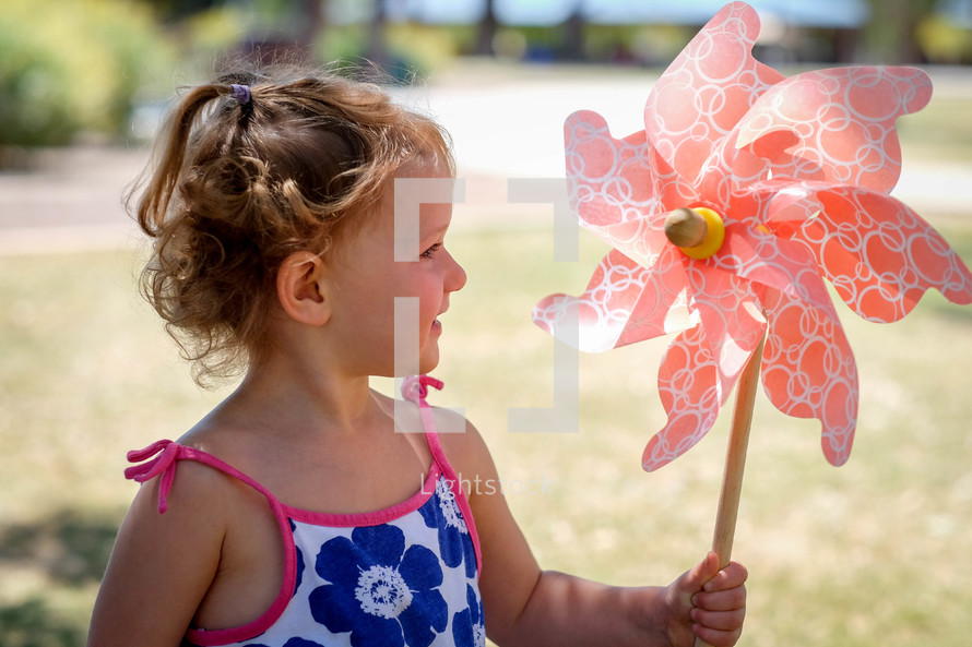 a toddler girl holding a pinwheel 