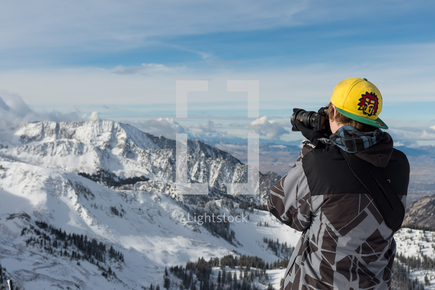 boy taking a picture of a snow capped mountain 