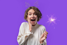 Pretty woman with sparkling bengal fire on violet background. Christmas holiday concept. Young girl with sparkler celebrating, smiling, enjoying time. High quality photo