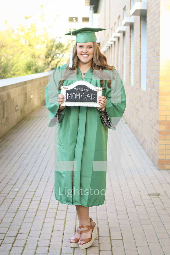 graduate holding a thanks mom and dad sign 
