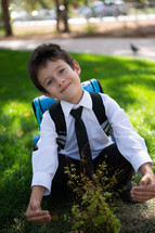 portrait of a boy in dress clothes with a book bag 
