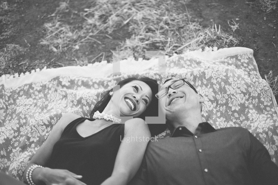 happy couple lying on a blanket in the grass 
