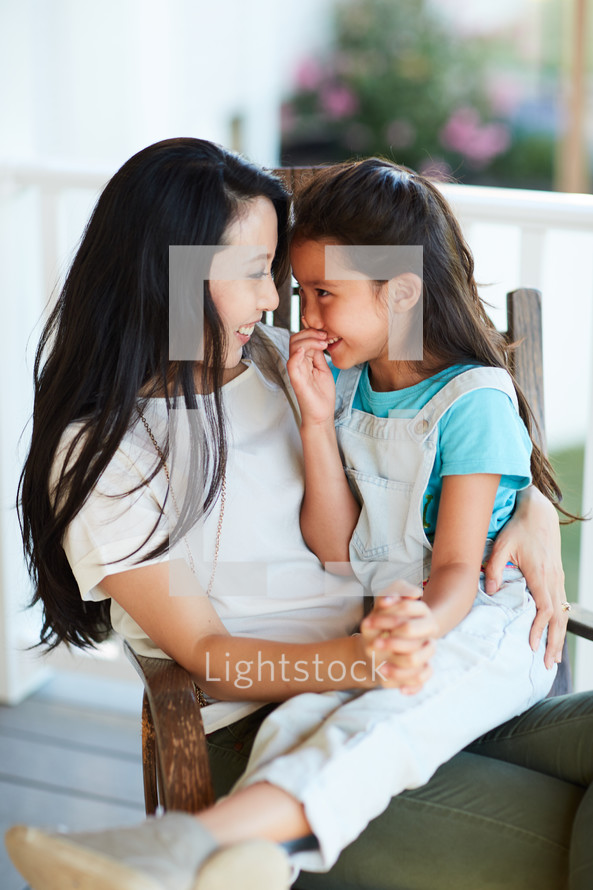 a mother and daughter talking on a porch 