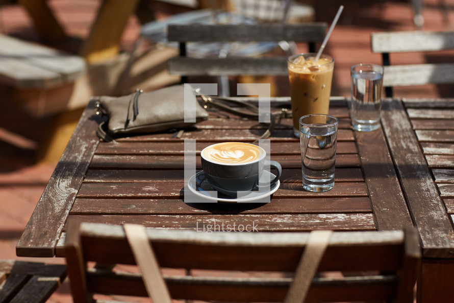 cappuccino and iced coffee on a wooden table outdoors 