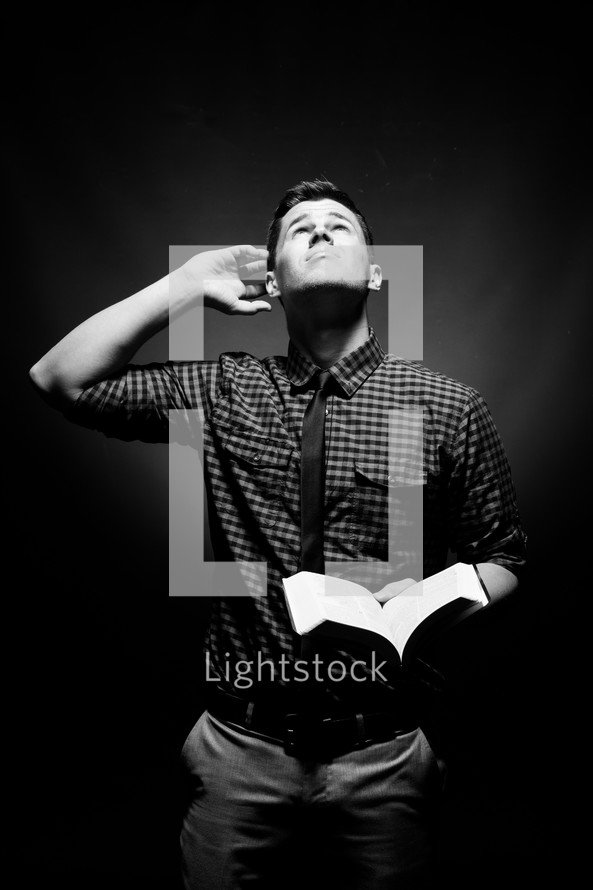 Can you hear me - a man holding a Bible and looking up to God