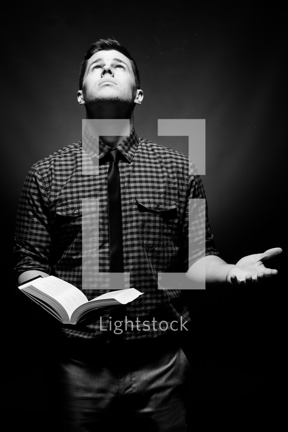 man holding a Bible and looking up to God