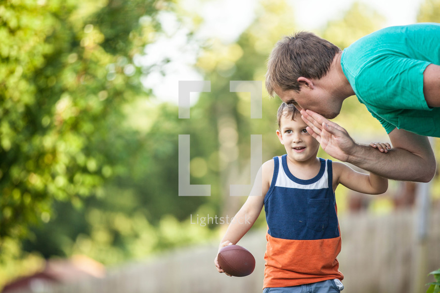 father and son playing football 