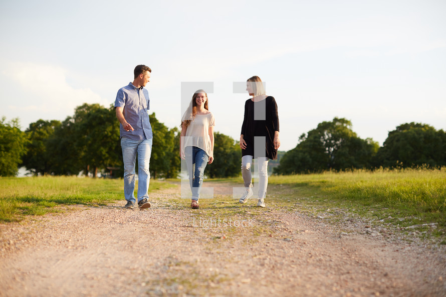 a mother and father walking and talking with their teenage daughter 