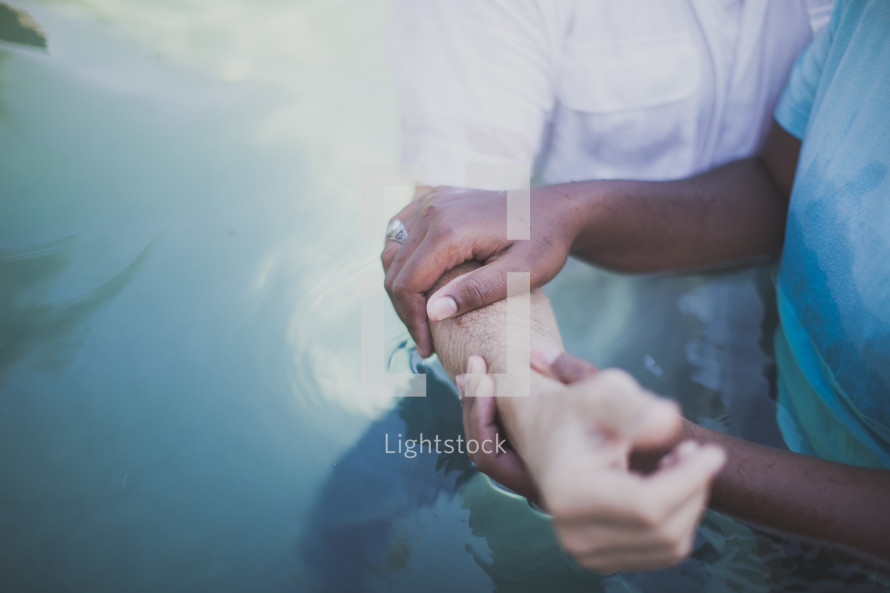 Hands holding and arm during baptism.