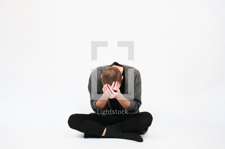 a man sitting holding his head down 