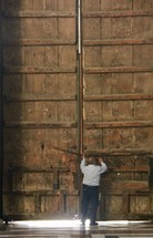 a man opening large wood doors 