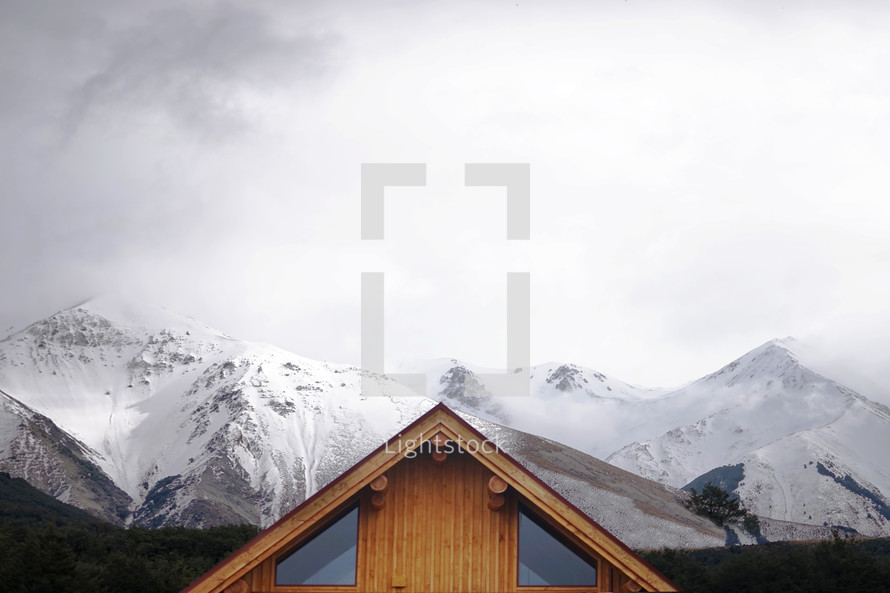 log cabin surrounded by snow capped mountains 