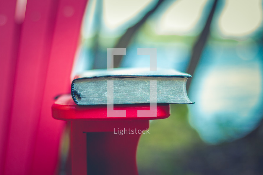 Bible on the edge of a red adirondack chair