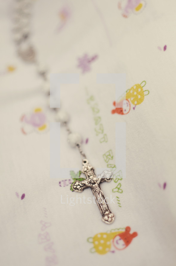 A cross necklace on a child's bedding. 