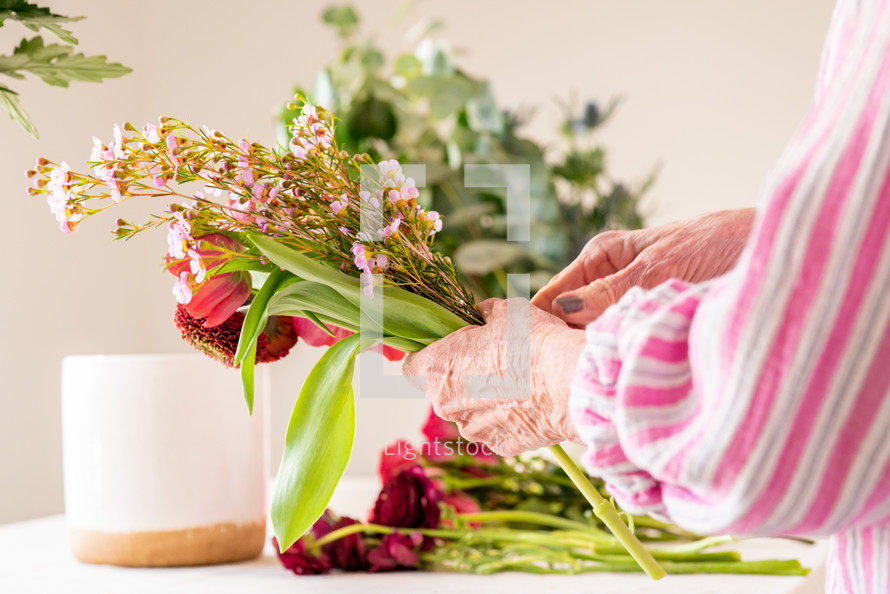 a senior woman arranging a bouquet of flowers 