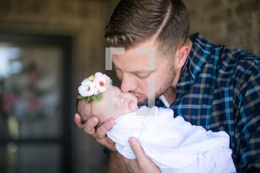 father with a swaddled newborn baby girl 