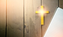yellow cross and notebook on a wood background 