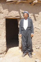 Kurdish man standing at an entrance to a desert home 