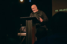 minister on stage giving a sermon during a worship service 