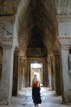 a woman walking through a covered stone corridor 