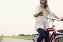 woman riding a bicycle holding flowers