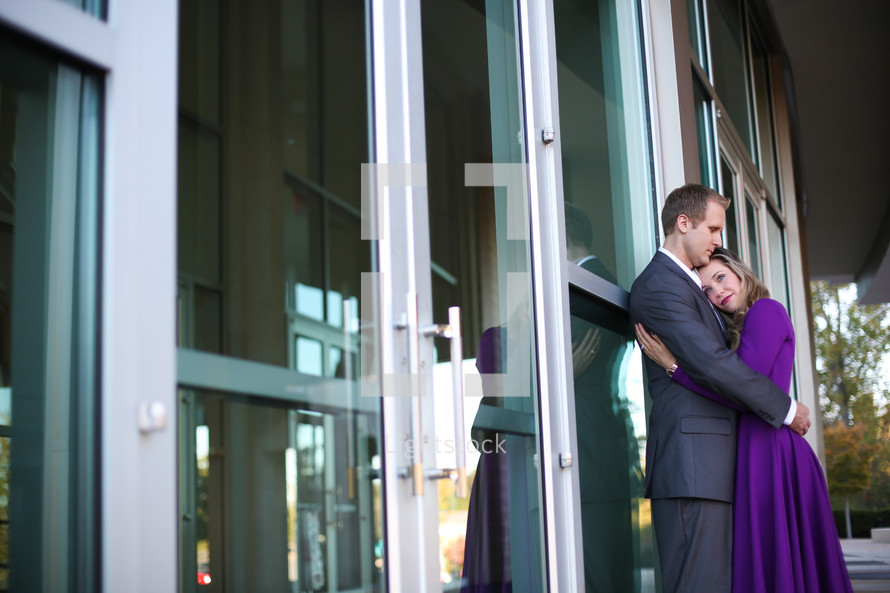 Man and woman hugging in front of a building.