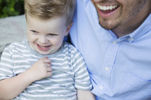 a smiling father and toddler son 