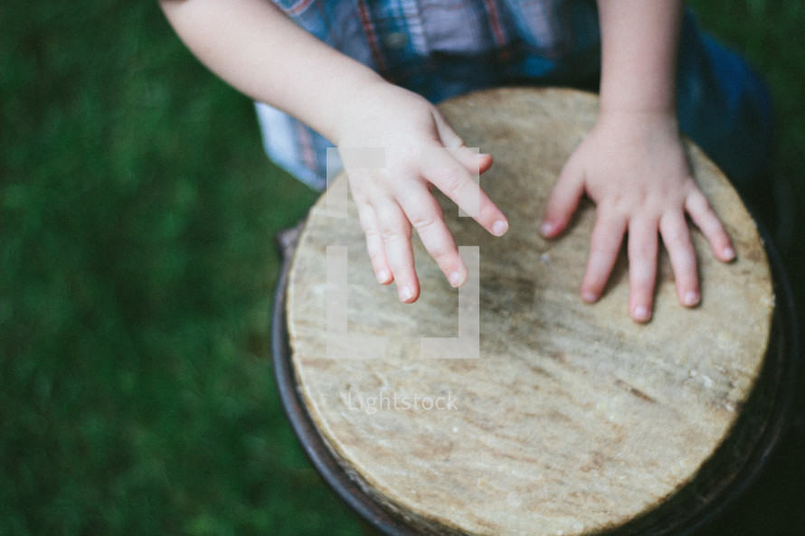A child's hands playing a drum 