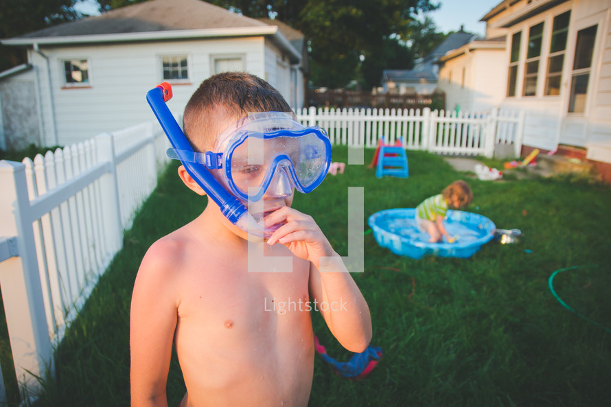 a little boy in a snorkel and goggles in the backyard 