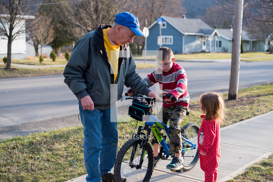 grandfather helping a boy ride a bicycle 
