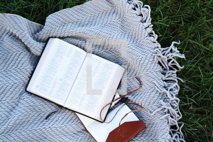 a Bible on a blanket in grass