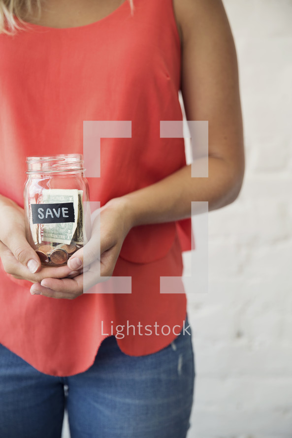 woman holding a save money jar 