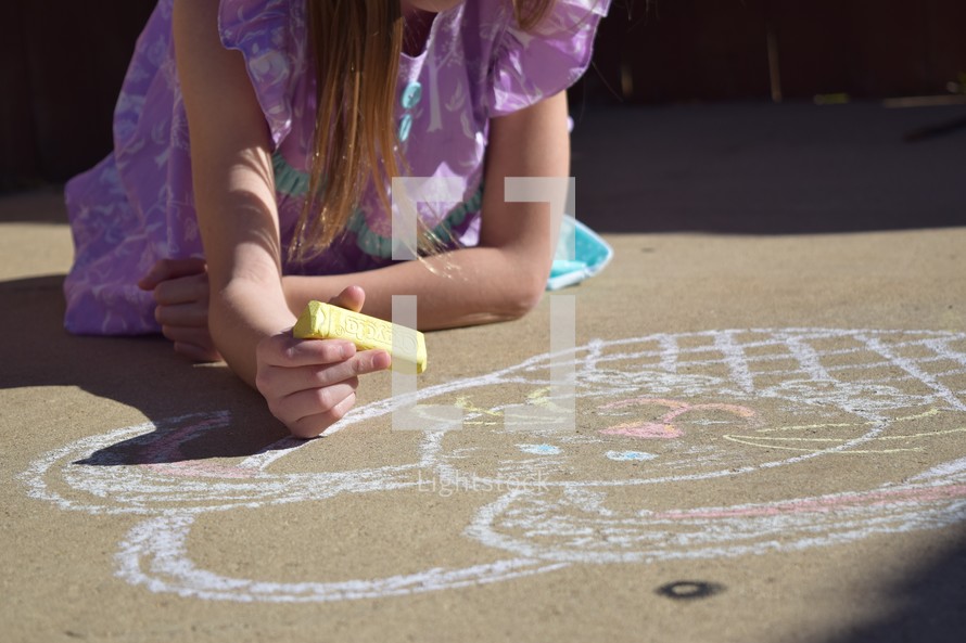 A little girl coloring an Easter bunny with sidewalk chalk
