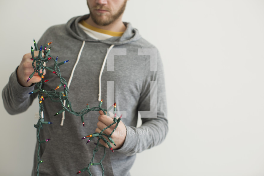 a man holding a string of tangled Christmas lights 