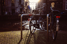 Bicycles in a bicycle stand next to a river.