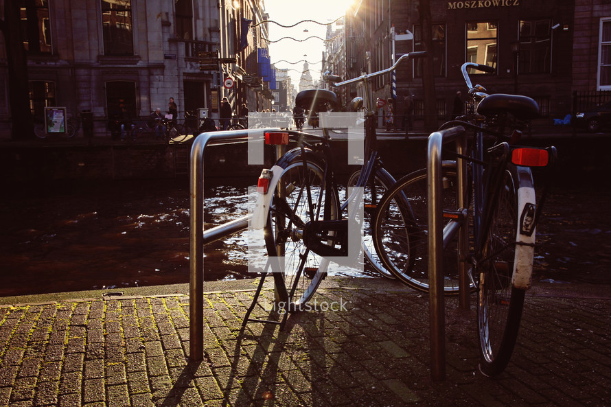 Bicycles in a bicycle stand next to a river.