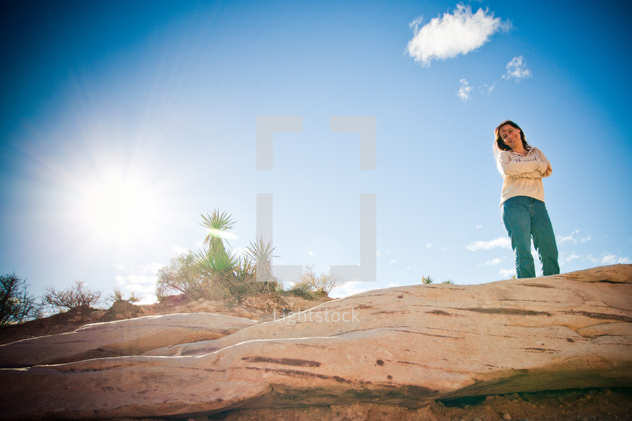 woman standing on top of a rock in a desert