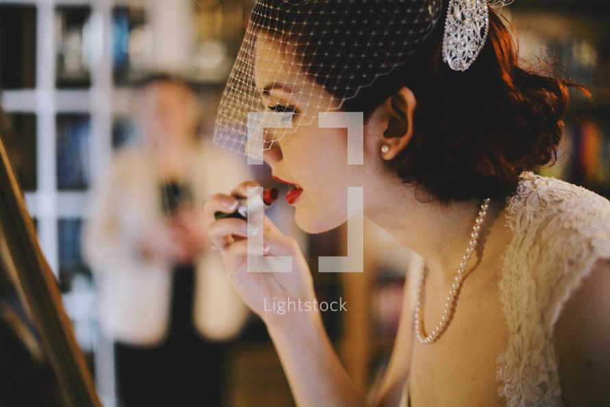 a bride putting on red lipstick 