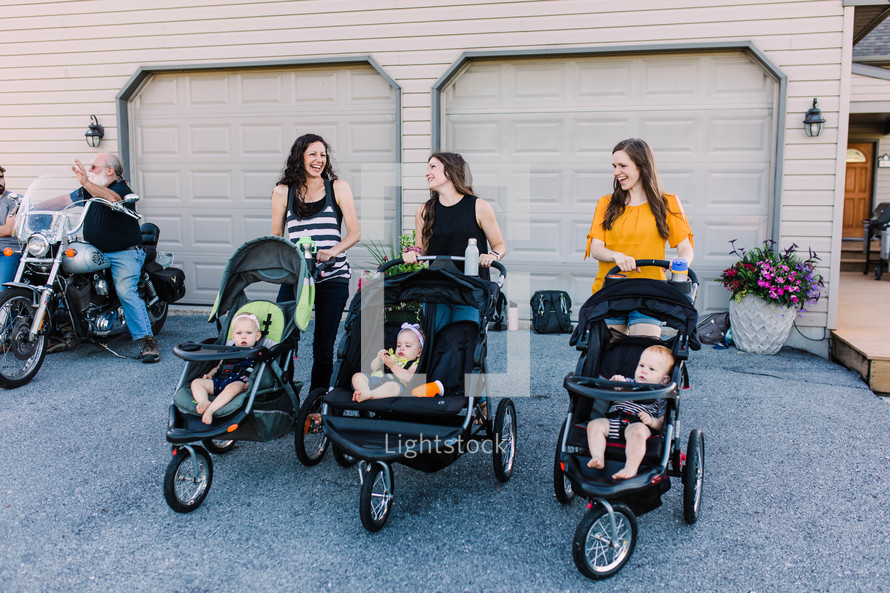 mothers standing together with babies in baby strollers 