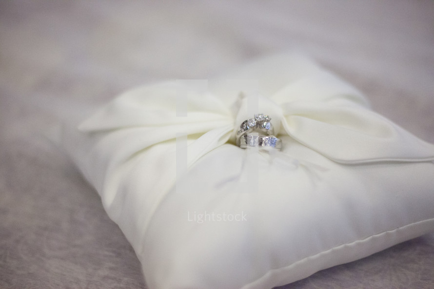 Wedding rings laying on a white pillow