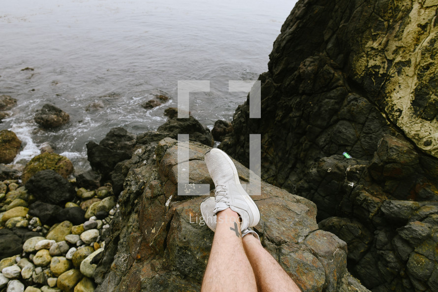 man sitting on a rocky shore 