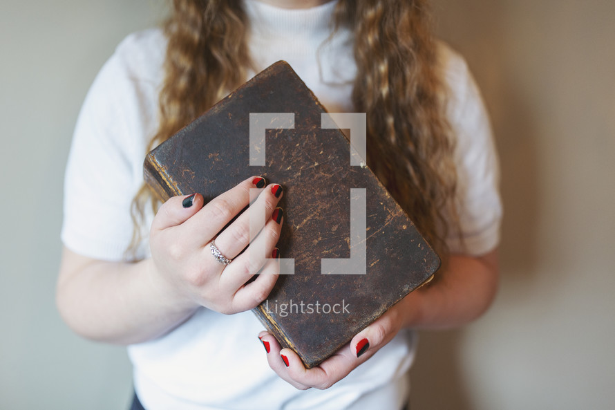 a young woman holding old Bible