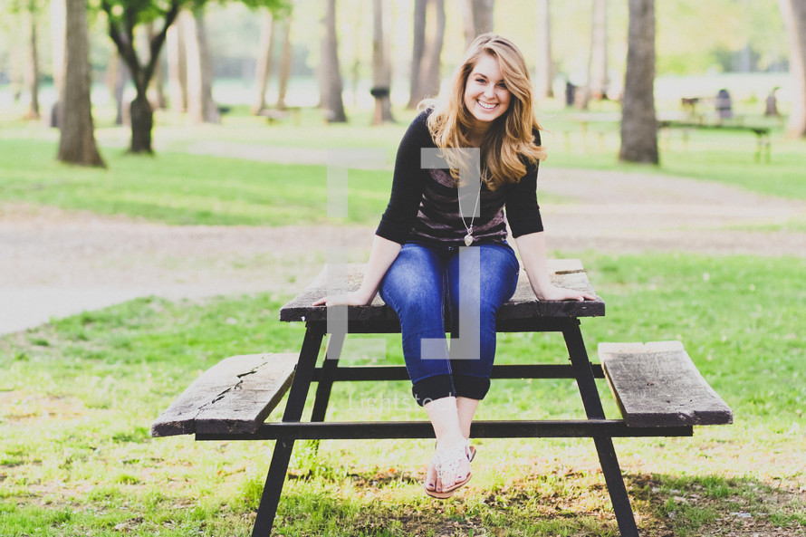 woman sitting on a picnic table in a park 