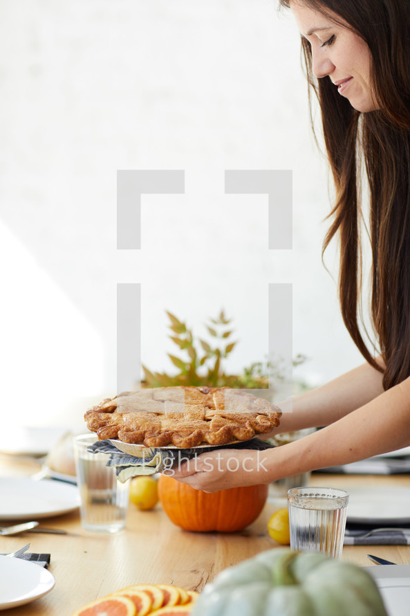 a woman putting a pie on a table 