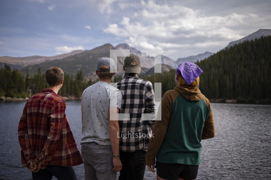 friends standing around a mountain lake 