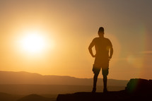 silhouette of a man standing at the edge of a mountaintop looking up 