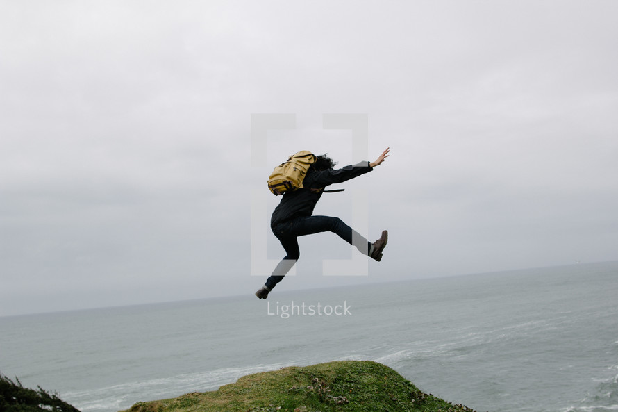 a man with a backpack leaping outdoors 